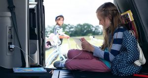 Young girl using tablet that is plugged into the Dodge Grand Caravan